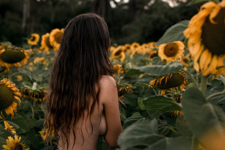 Naked woman is walking around sunflowers